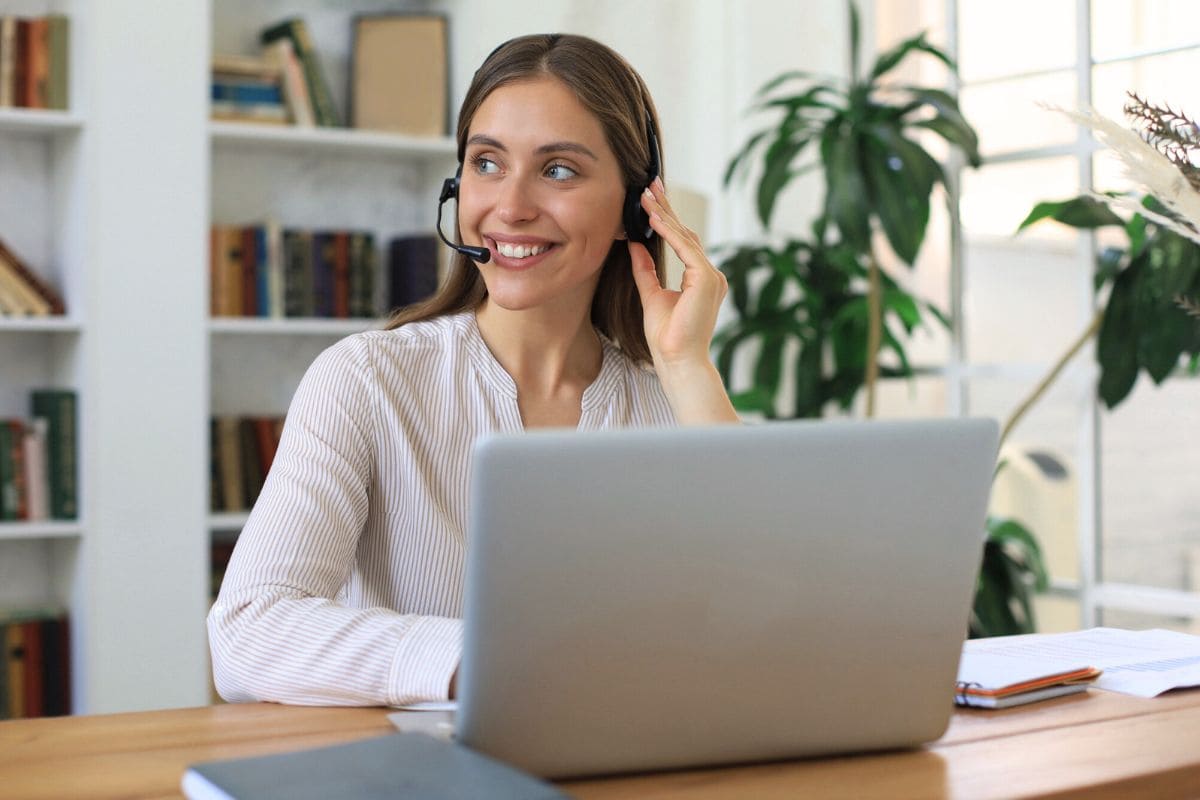 A remote dispatcher working from her home office on a laptop and using a headset for remote dispatcher jobs