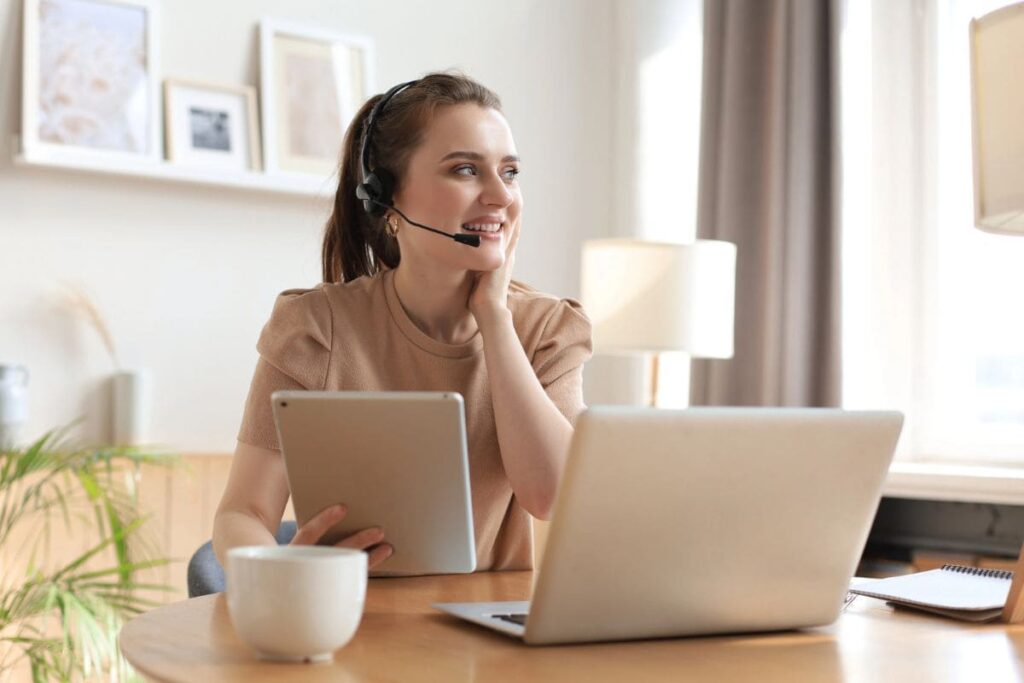 A remote dispatcher working from her home office on a laptop and using a headset.