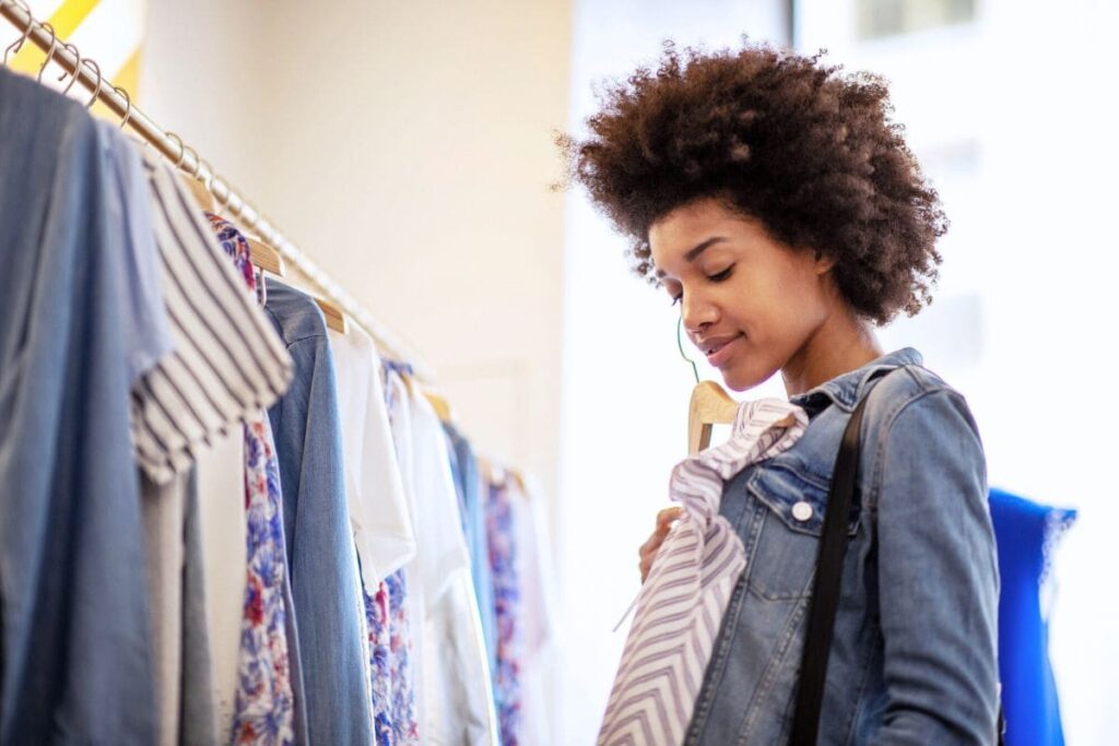 A mystery shopper holds up clothes in a retail store.