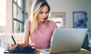 A virtual assistant working from home at her kitchen table and using a laptop.