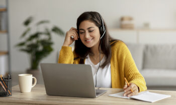 A woman wearing a sweater and headset working her Alorica work from home job