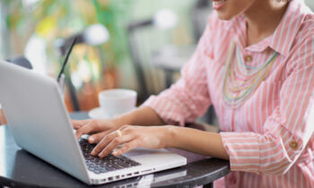 A young woman in a cafe working on her laptop reading about small business ideas online
