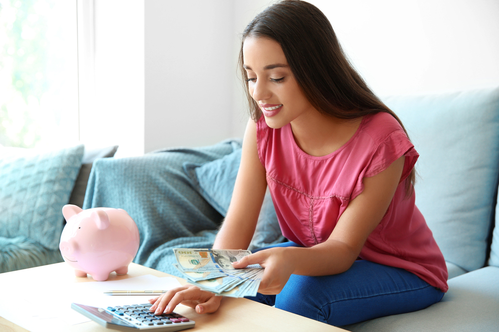 A young woman with long hair counting money from her job that pays daily