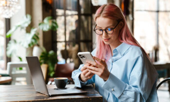 A young woman with pink hair and glasses working her no set schedule job at a cafe