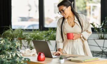 A woman reviewing her career goals on her laptop while drinking coffee.
