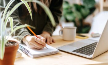 A woman working from home at a desk, surrounded by plants for blog post how to create a course