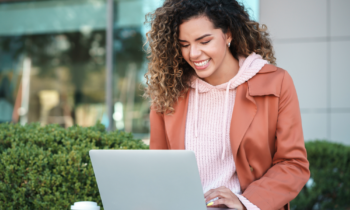 Young woman working outdoors on her laptop for her Fiverr jobs